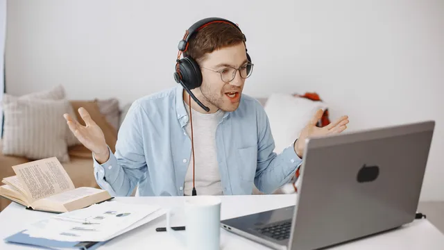Mann mit Headset gestikuliert genervt vor seinem Laptop