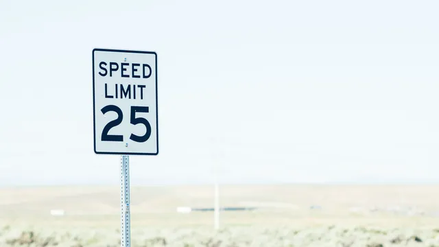 Schild mit Tempolimit am Rand einer weiten, hellen Ebene