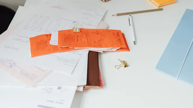 Heller Schreibtisch mit Belegen, Rechnungen und Büroklammern