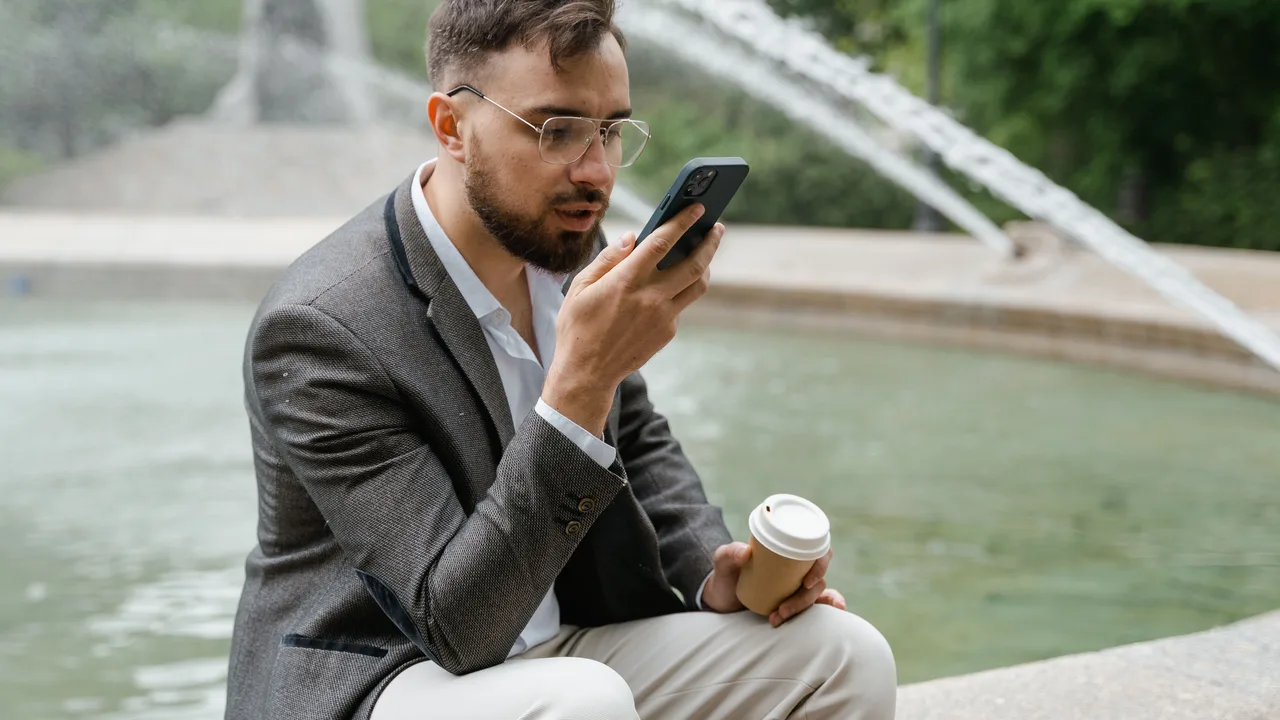Geschäftsmann spricht unterwegs eine Sprachnachricht ins Smartphone